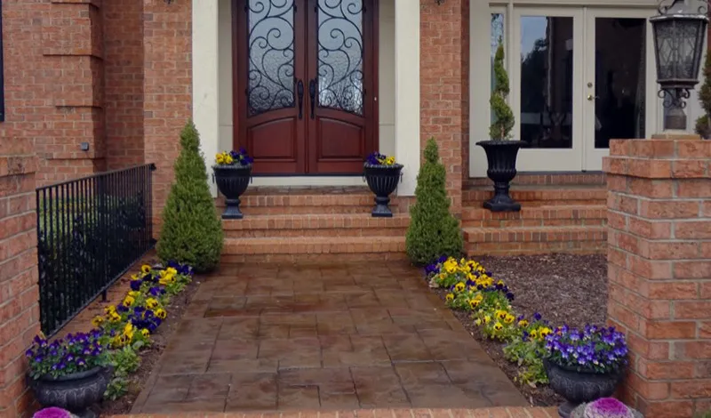 Brown stamped concrete walkway with brick border installed in Charlotte, NC by Stamped Concrete Artisans